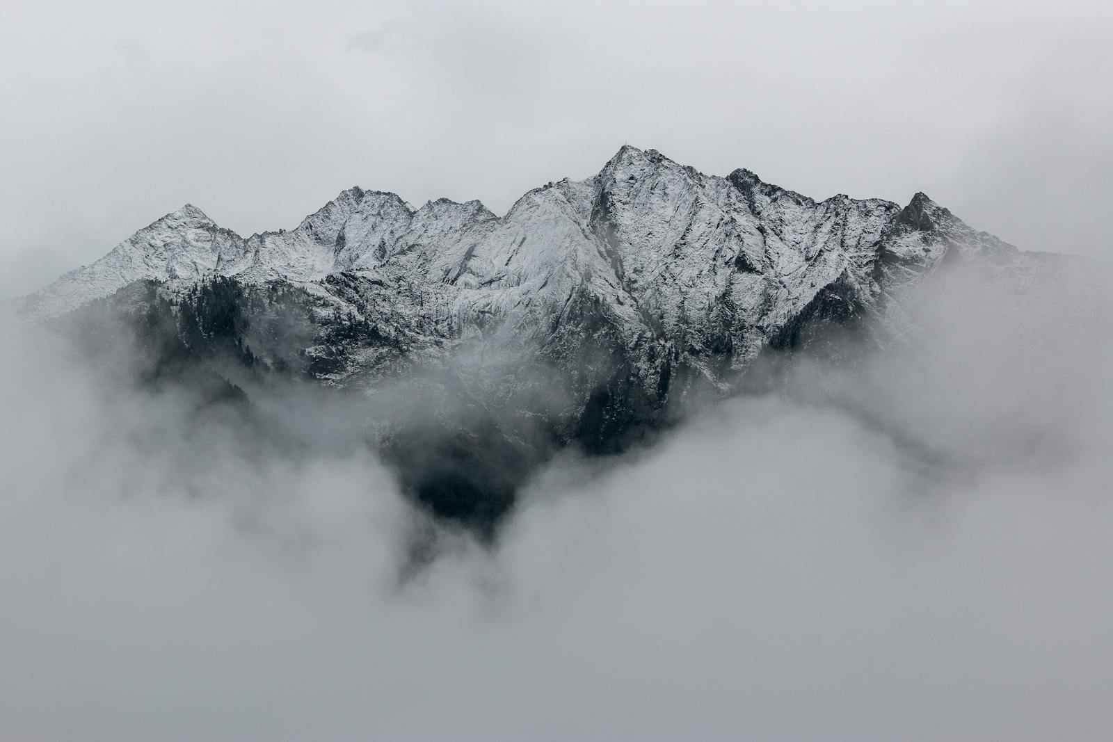 Snow Covered Mountain Peaks in Dense Fog