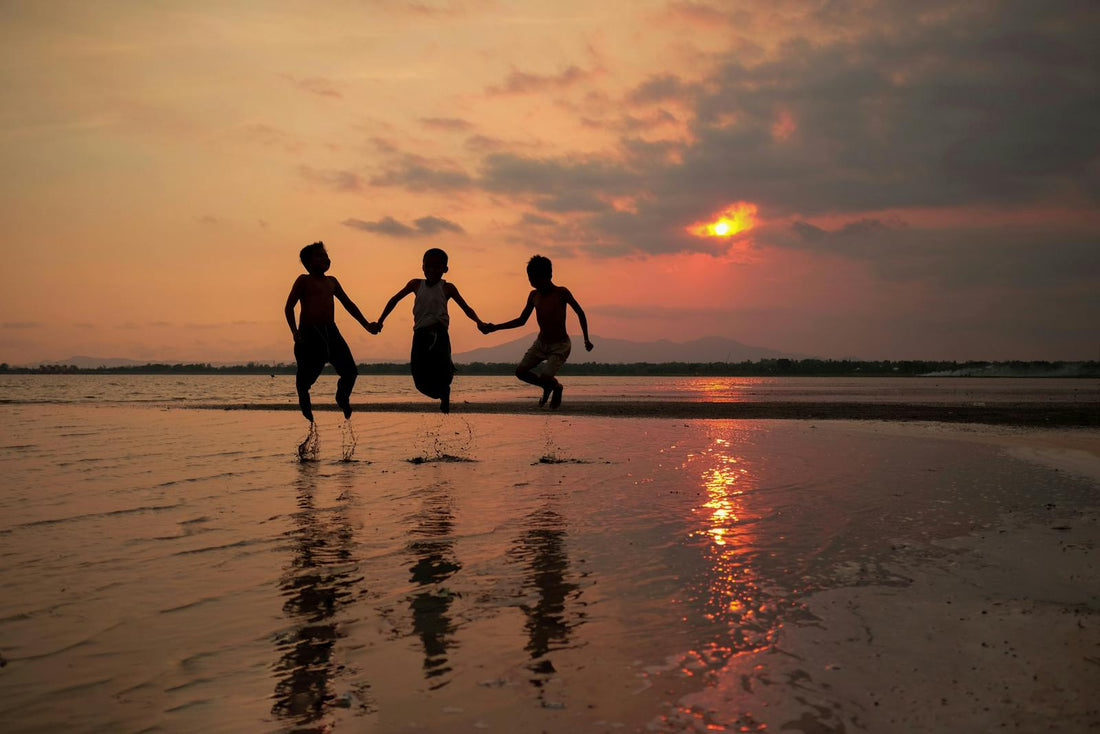Three kids jump on the beach at sunset in Indonesia