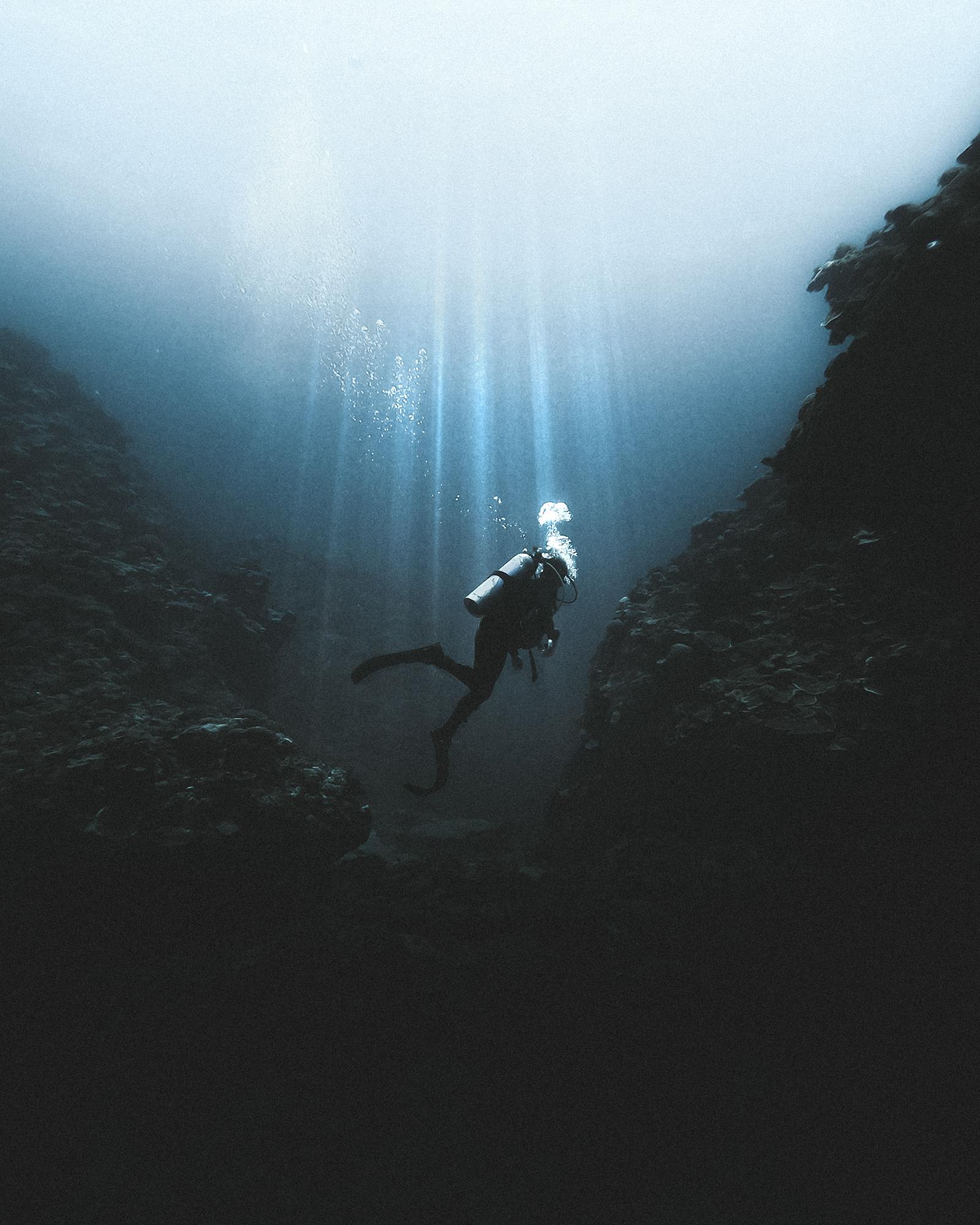 Scuba diver explores deep sea formations