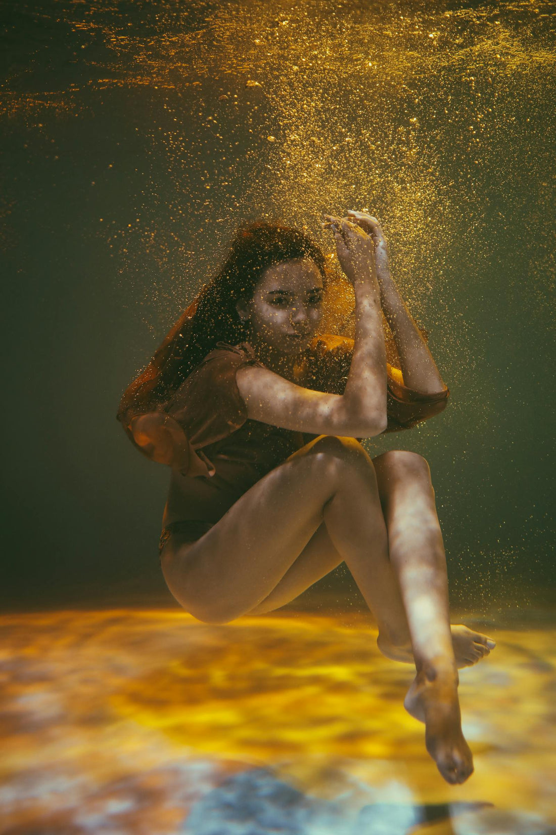 Woman poses underwater with floating things